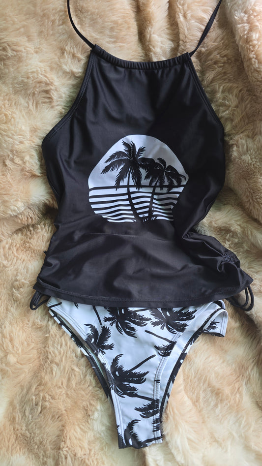 Black and white bikini set with palm tree design on a textured surface