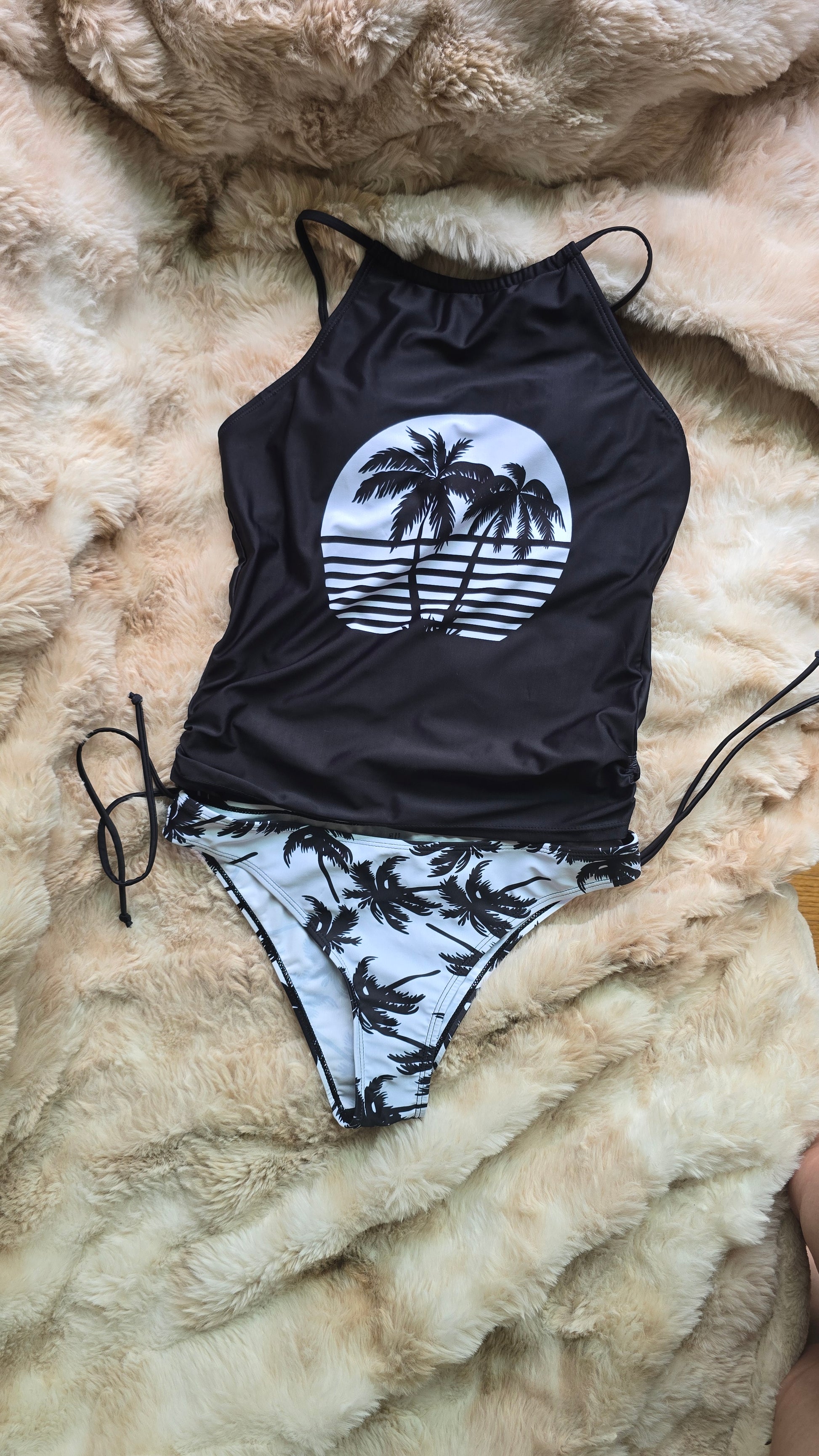 Black and white swimsuit with palm tree design on a fluffy beige surface