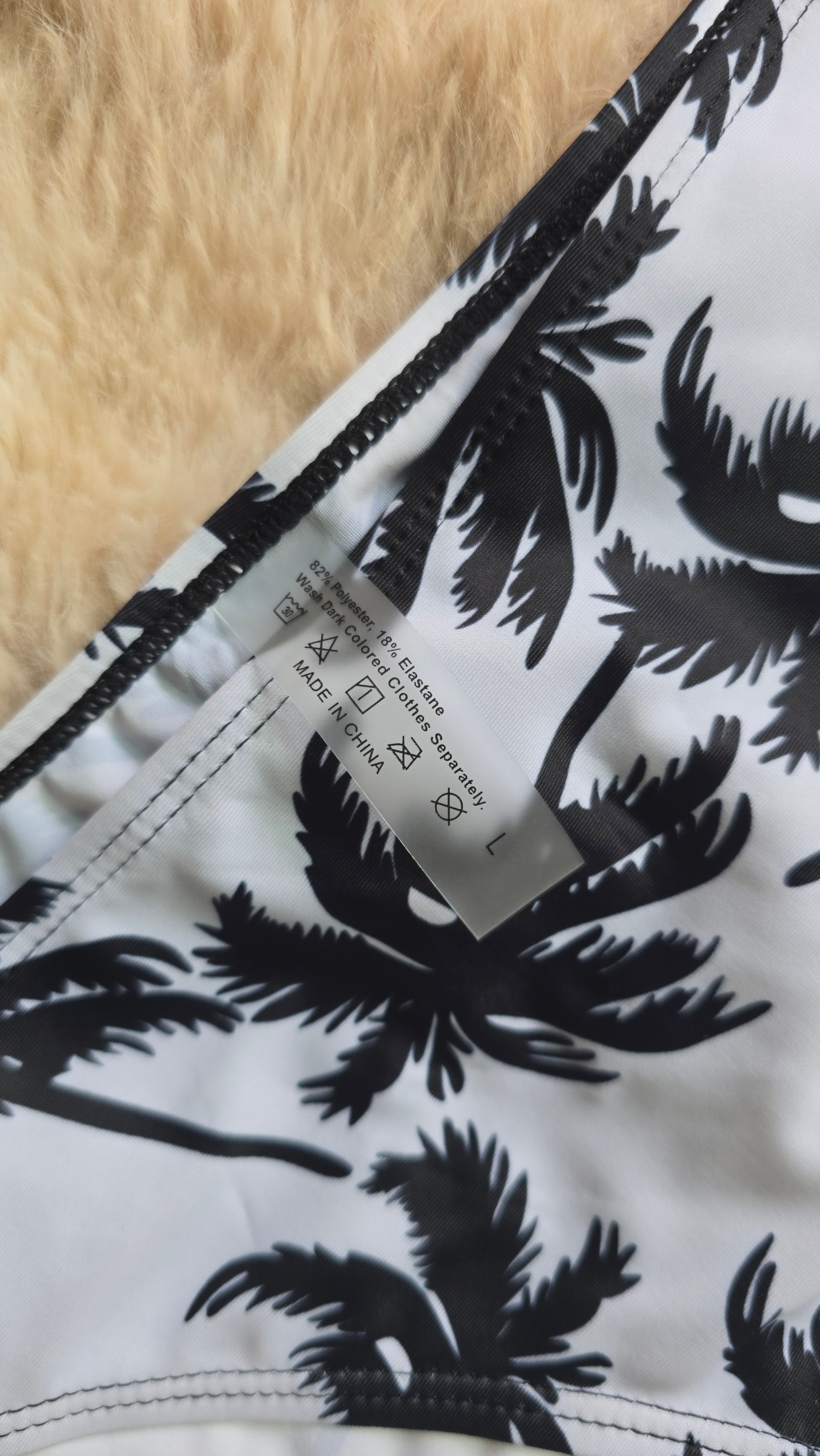Close-up of a fabric with black palm tree pattern on white, showing a label.