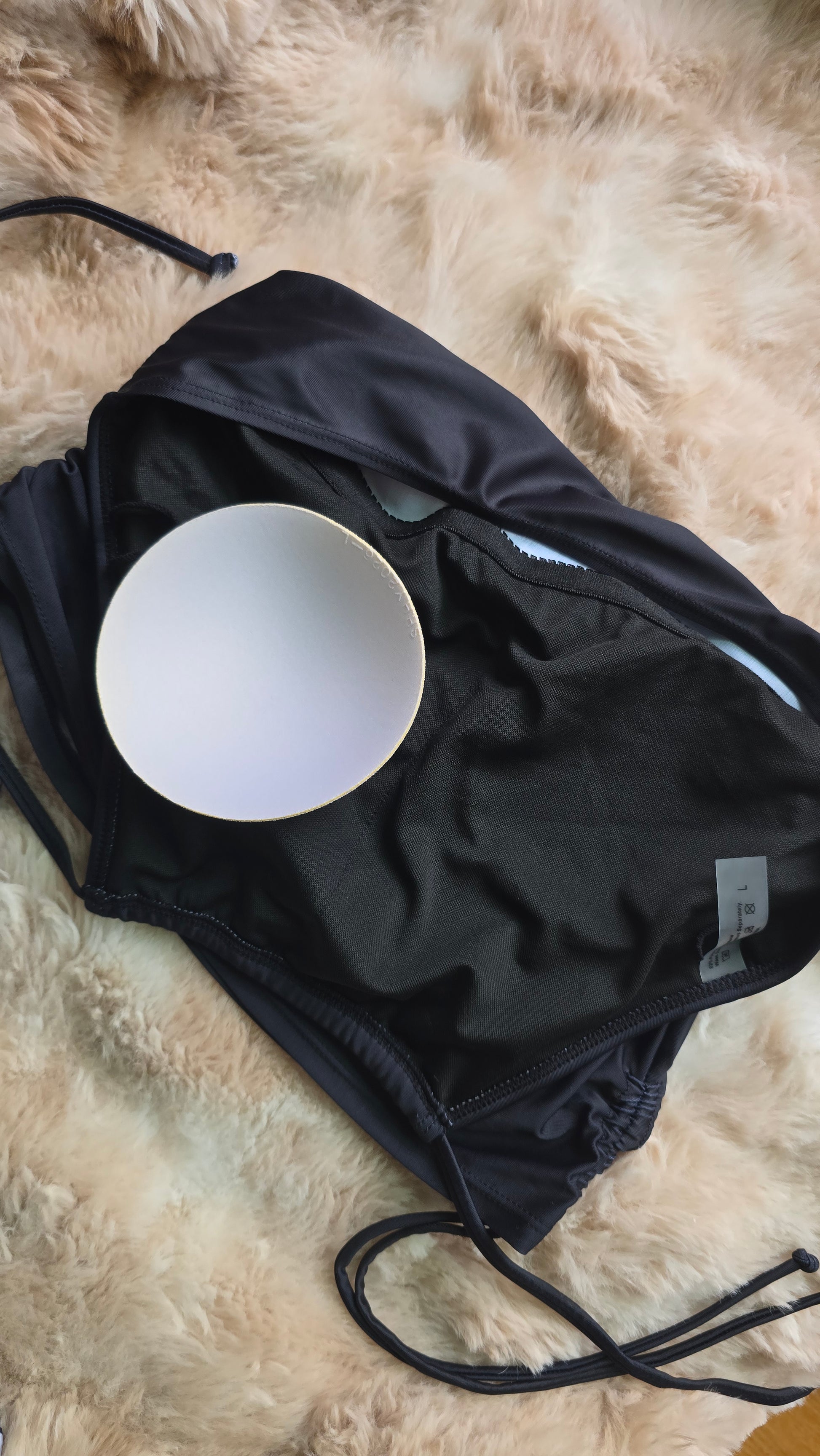 Black swimsuit with a white bowl inside on a fur surface